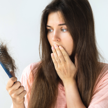 Woman in disbelief while losing her hair in the hairbrush