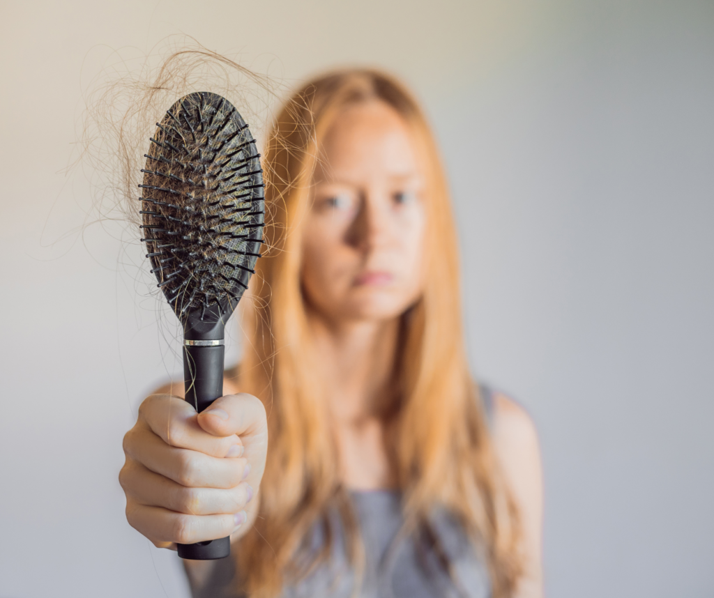 woman holding brush with hair fallen out