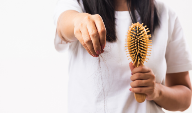 Woman pulling fallen hair from hair brush